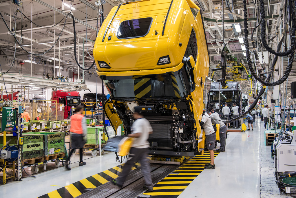 Workers assembling truck chassis at an assembly line Workers assembling truck chassis at an assembly line